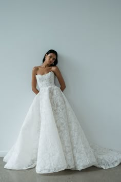 a woman in a wedding dress leaning against a wall