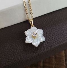 "A beautiful mother of pearl flower charm necklace with cz accent in the center. 14k gold filled cable chain 16-18\" or 18-20\" adjustable chain Flower charm 14x16mm without the bail" Luxury Pearl Flower Pendant Jewelry, White Flower Necklace, Gold Necklace Flower, Elegant White Flower Necklace With Birth Flower Detail, Elegant White Flower Necklace For Birth Month, Elegant White Flower Necklace For Birthdays, Elegant White Birth Flower Necklace, White Mother Of Pearl Jewelry With Flower Charm, Dainty White Flower Necklace For Anniversary