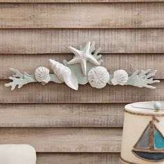 a sea shell and starfish decoration on the side of a wooden wall next to a lamp