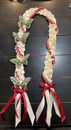 two wreaths with red and white ribbons are hanging on a wooden wall in the shape of an oar