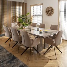 a dining room table with beige chairs around it