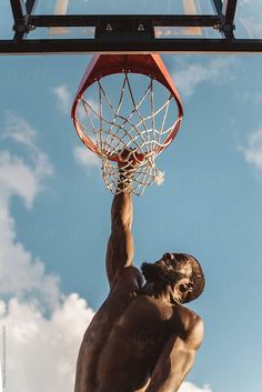 a shirtless man dunking a basketball into the hoop by jovan risticic for stocks