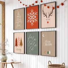 four framed holiday cards hang on the wall above a table with a basket and vase