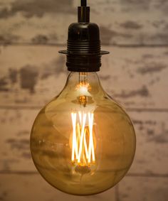 an old fashioned light bulb hanging from a ceiling fixture with wood planks in the background