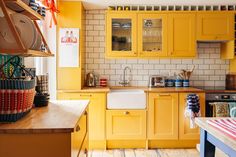 a kitchen with yellow cabinets and wooden floors