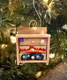 an ornament hanging from a christmas tree decorated with colorful designs on it's sides