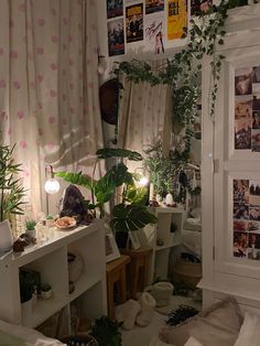 a living room filled with lots of plants next to a wall covered in posters and pictures