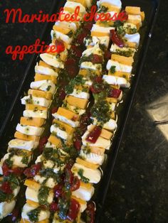 many different types of appetizers are arranged on a black tray with the words marinated cheeses above them