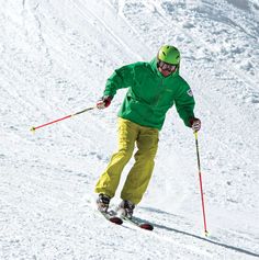 a man riding skis down the side of a snow covered slope with ski poles