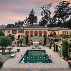 an aerial view of a large house with a pool in the foreground and trees surrounding it