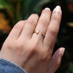 a woman's hand with a gold ring on top of her finger and a diamond in the middle