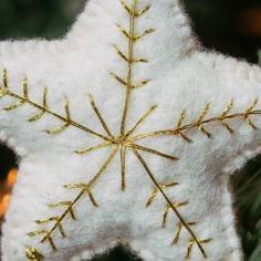 a white and gold star ornament hanging from a christmas tree