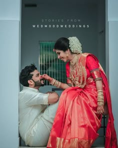 a man kneeling down next to a woman in a red and gold sari on her wedding day