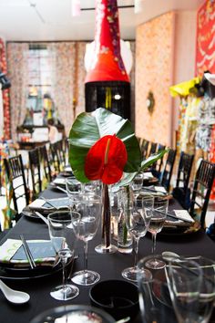 the table is set with many empty wine glasses and place settings, including one red flower