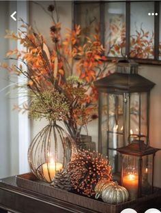 an arrangement of candles and flowers on a mantle in front of a window with fall foliage