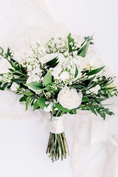 a bridal bouquet with white flowers and greenery