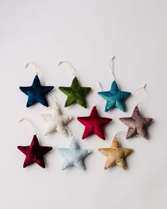 six star ornaments hanging from strings on a white surface