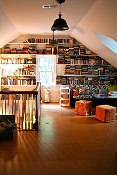 a living room filled with lots of books on top of a wooden floor next to a window