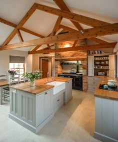 a large kitchen with an island in the middle and wooden beams on the ceiling above it