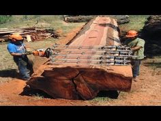 three men are working on a large piece of wood