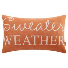 an orange and white pillow with the words, sweater weather on it's side