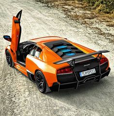 an orange sports car with its doors open