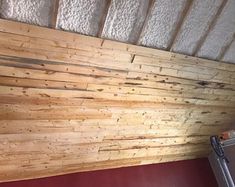 an unfinished room with wood paneling on the ceiling