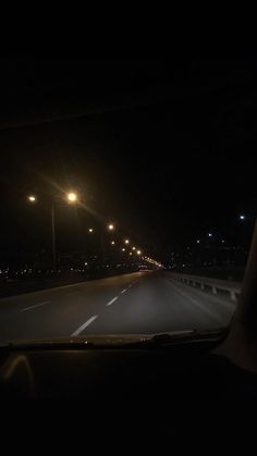 the dashboard of a car at night with street lights in the distance and dark sky