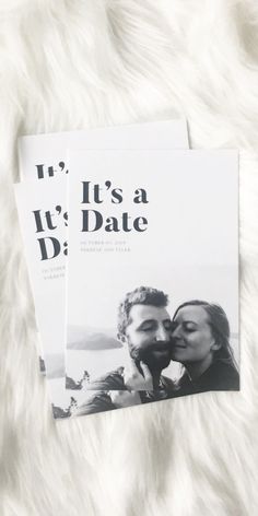 two magazine covers sitting on top of a white fur covered surface, with the title it's a date written in black