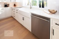 a clean kitchen with white cabinets and stainless steel dishwasher in the center island