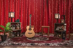 an acoustic guitar sitting on top of a rug in front of red curtained walls