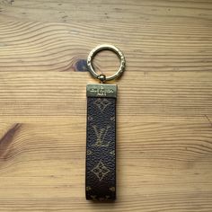 a louis vuitton keychain on top of a wooden table with a metal ring