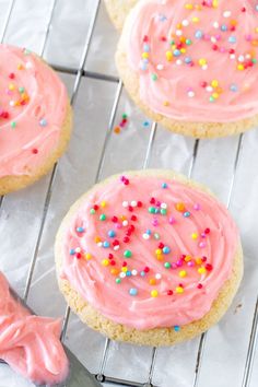 cookies with pink frosting and sprinkles on a cooling rack, ready to be eaten