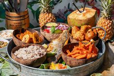 there are many different types of food in the trays on this table, including pineapples and other foods