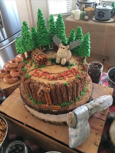 there is a cake that looks like a log with a bear on it and pine trees