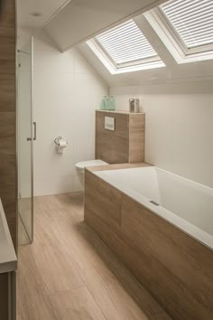 a bathroom with a large bathtub next to a sink under a slanted window