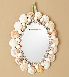 a mirror hanging on the wall with seashells around it