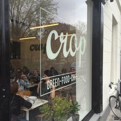 a group of people sitting at tables in front of a store window with the word crop written on it