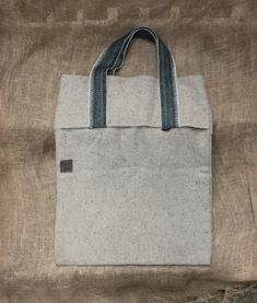 a white and blue bag sitting on top of a brown cloth covered bedding area