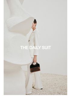 a woman in white is holding a black handbag and posing for the daily suit