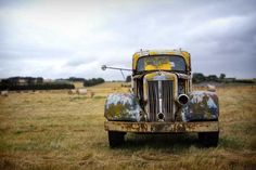 an old yellow truck parked in a field