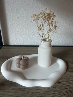 there is a vase with some flowers in it on the tray next to two balls