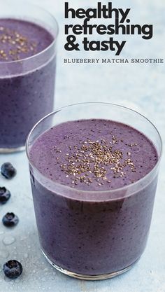 two glasses filled with blueberry matcha smoothie on top of a white table