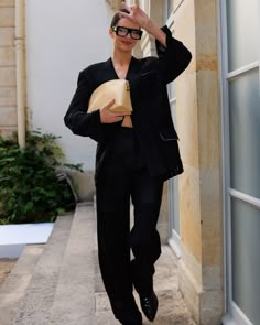 a man in black suit and sunglasses walking down the street