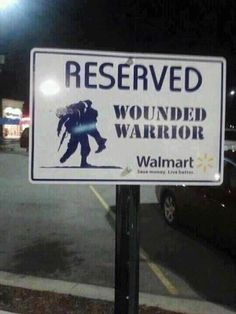 a sign that reads reserved wounded warrior walmart on the side of a street at night