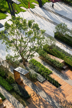 an aerial view of a park with benches, trees and walkways in the foreground