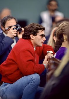 a man in red jacket sitting next to other people