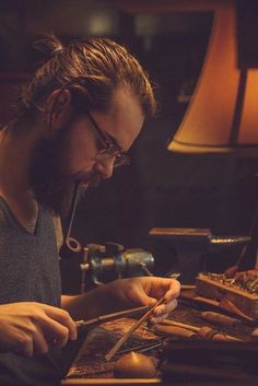 a man with long hair and glasses working on something