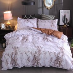 a bed with white and brown comforters in a room next to a lamp on a table