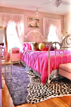 a bedroom with pink bedding and accessories in it's centerpiece, along with an animal print rug on the floor